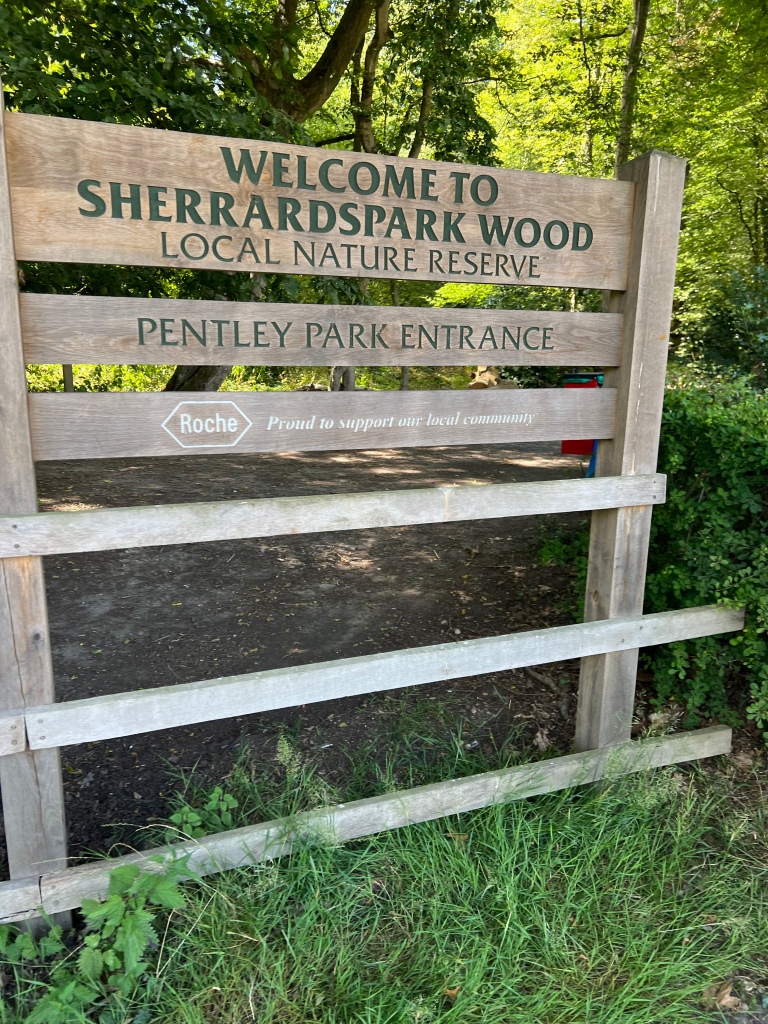 The sign like the Reddings one has the 3 planks with text 
“Welcome to Sherrardspark Wood Local Nature Reserve”
“Pentley Park Entrance”
“Roche Proud to support our local community”
In addition beneath the signage there are 3 thinner planks which are a continuation of the wooden fence either side of the path into the woods.